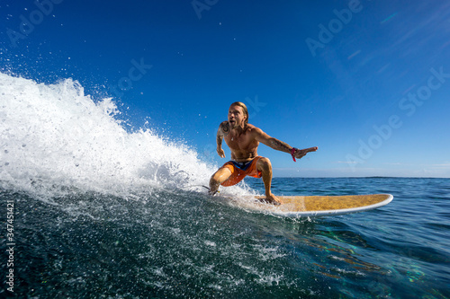 muscular surfer with long white hair riding on big waves on the Indian Ocean island of Mauritius © ohrim