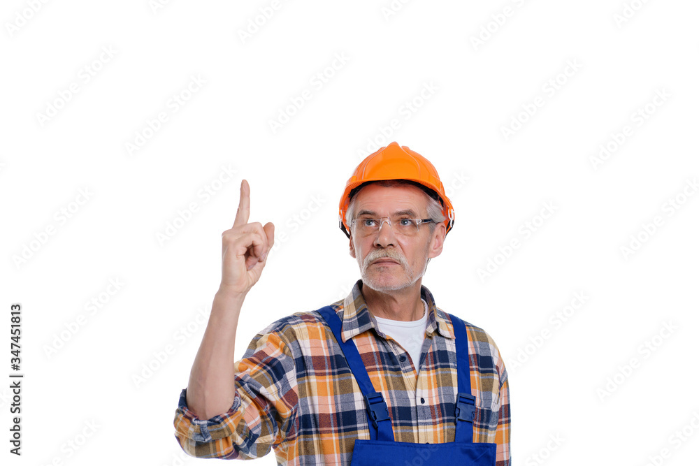 Photo of a old male builder in a helmet looking above it , isolated on white wall background, repair, construction, building concept Photo of a old male builder in a helmet looking above it , isolated on white wall background, repair, construction, building concept