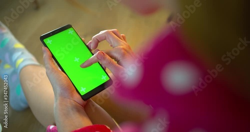 girl in a bathrobe uses a phone with a green screen