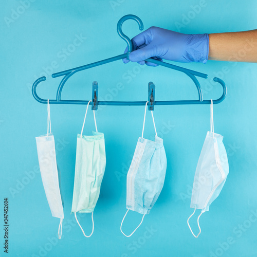 fashion outfit at pandemic time. face masks hanging on a rack over pastel blue background.