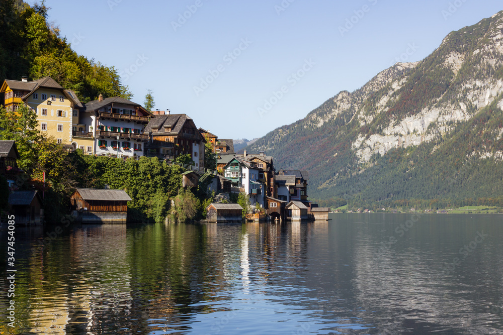 Traditional Austrian houses built on hillside surrounded by natural lake and mountains in the Alps