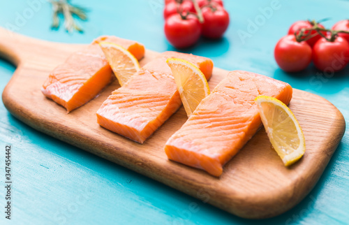 Delicious salmon steak on wooden cutting board, close-up.