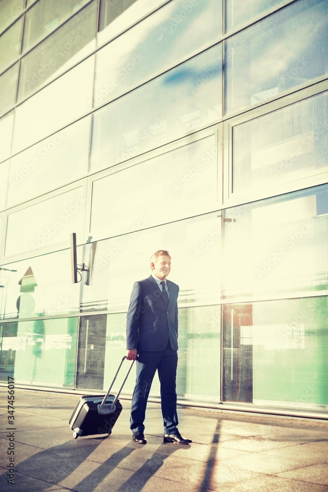 Portrait of mature businessman walking with his suitcase in airport Portrait of mature businessman walking with his suitcase in airport
