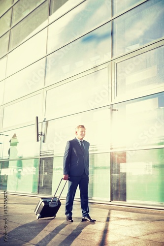 Portrait of mature businessman walking with his suitcase in airport