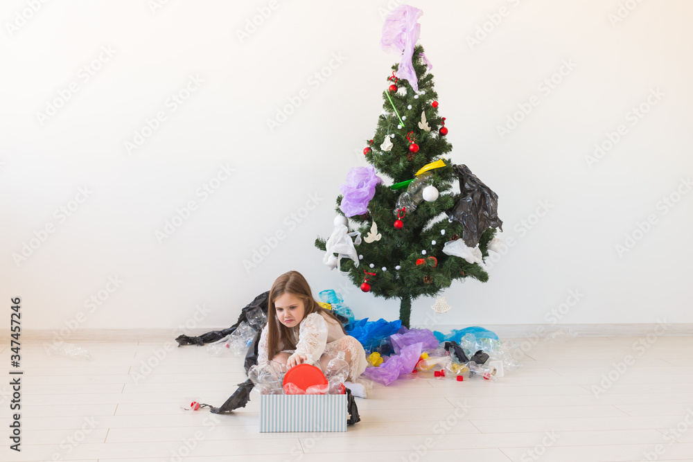 Environmental protection and pollution concept. Surprised child carrier box with plastic trash over christmas tree background. Environmental protection and pollution concept. Surprised child carrier box with plastic trash over christmas tree background.