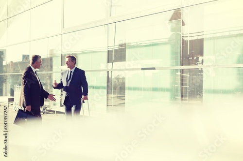 Portrait of businessmen talking while waiting for taxi in airport