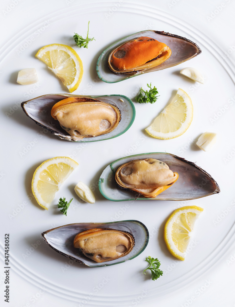 New Zealand Mussels with slices lemon, parsley and garlic, on white ceramic dish