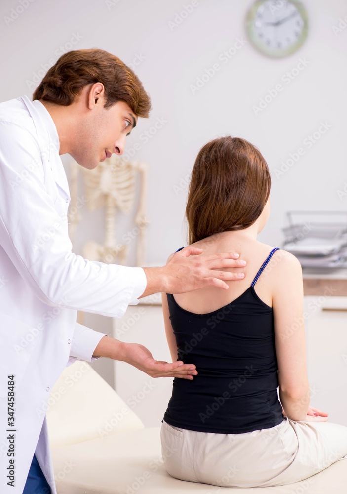 Fototapeta premium Female patient visiting young handsome doctor chiropractor