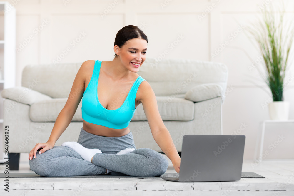 Slim Woman Practicing Yoga At Laptop Watching Online Videos Indoors Slim Woman Practicing Yoga At Laptop Watching Online Videos Indoors