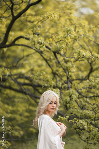 Fototapeta Naklejka Na Ścianę i Meble -  Blonde girl in a dress enjoys spring nature