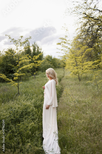 Blonde girl in a dress enjoys spring nature