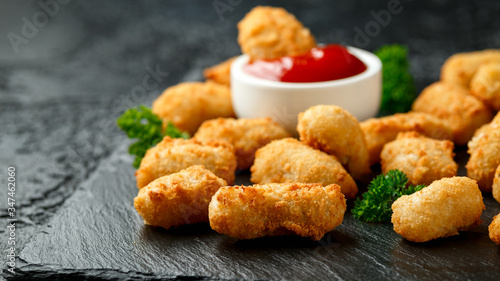 Crispy Battered scampi nuggets with ketchup and mayonnaise on rustic stone board.
