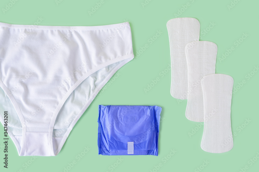 White underpants, few disposable panty liners and regular sanitary pad on a pastel mint background. Flat lay of feminine hygiene items. White underpants, few disposable panty liners and regular sanitary pad on a pastel mint background. Flat lay of feminine hygiene items.