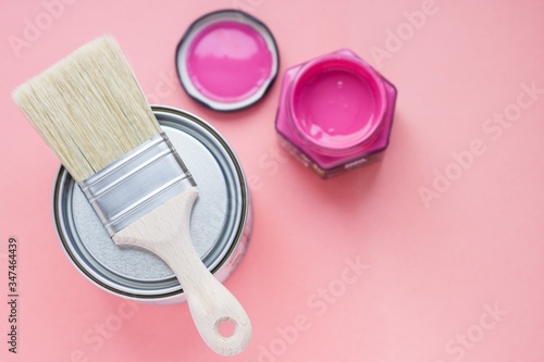 Paint can with purple paint and new brush on pink background. House renovation. Hobby. Color therapy.