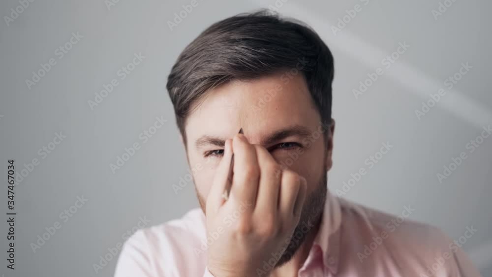 Close-up of a bearded handsome man plucking hair between his eyebrows with tweezers Close-up of a bearded handsome man plucking hair between his eyebrows with tweezers
