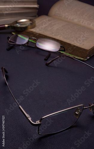 Books with glasses on black table and wooden background. High resolution image depicting reading/bokks industry. photo