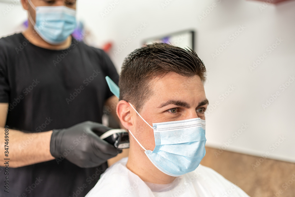 Man Getting Hair Cut at the Barbershop Wearing Mask. Covid-19 Concept.