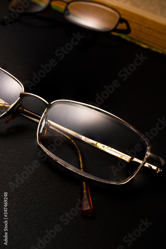 Books with glasses on black table and wooden background. High resolution image depicting reading/bokks industry. photo