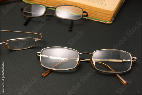 Books with glasses on black table and wooden background. High resolution image depicting reading/bokks industry. photo