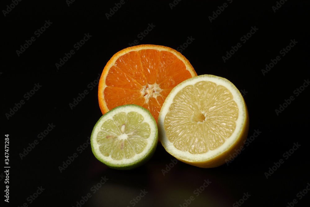 Still life of open citrus fruits composed of orange, lemon and lime on a black background Still life of open citrus fruits composed of orange, lemon and lime on a black background