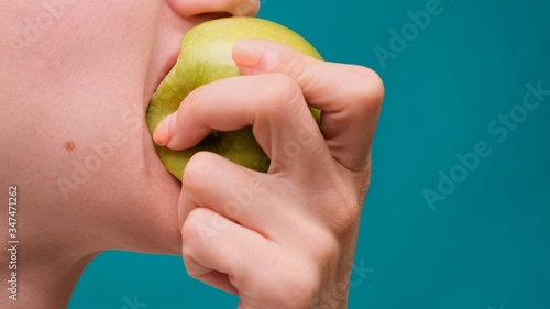 Healthy eating and healthy teeth or diet, young woman bites a fresh apple on a green screen close-up