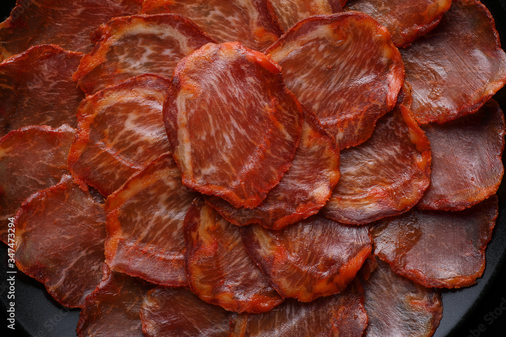 Φωτογραφία Close-up (detail) of a portion of acorn-fed Iberian loin on a black plate on a b