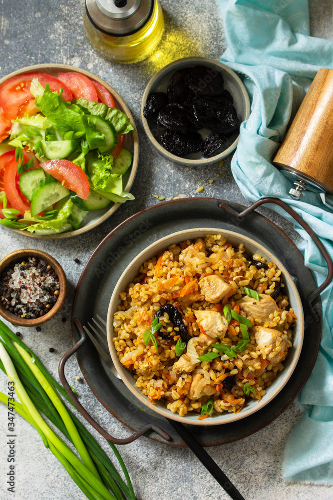 Bulgur pilaf. Healthy eating concept. Bulgur with chicken, vegetables and prunes on a gray stone or slate countertop. Top view flat lay background.
