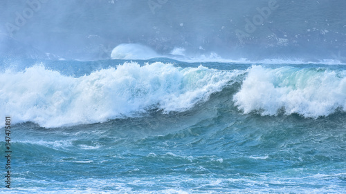 Big waves hit the rocks in rough seas. On a cloudy day. Galicia Spain.