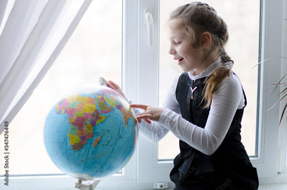 girl playing with a globe, looking for a country, at home school, on the window girl playing with a globe, looking for a country, at home school, on the window