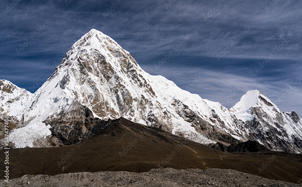 A towering peak of Pumo Ri Mountain peak in the Everest region of Nepal. Below the mountain peak, Kalapatthar, a popular viewpoint of Mt. Everest and hiking destination in the Everest region of Nepal.