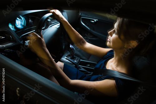 Driving a car at night - pretty, young woman driving her modern car at night in a city (shallow DOF; color toned image)