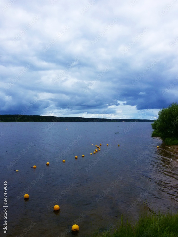 Yellow restrictive buoys on the bank of a wide reservoir in cloudy weather