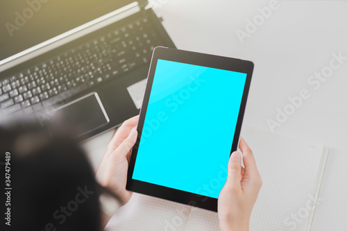 Technology concept: Woman holding a mock up of digital tablet device with Clipping path and notebook on white table in the background.