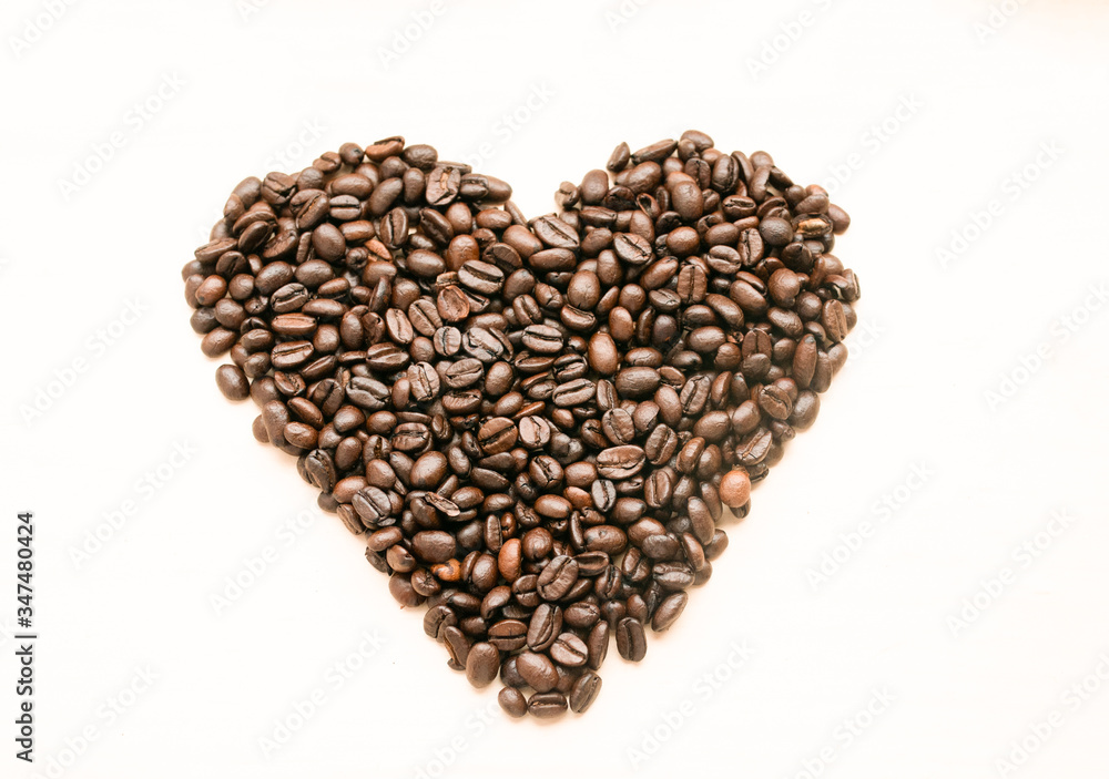 The shape of the heart is laid out on a light background of roasted coffee beans, there is room for text. The shape of the heart is laid out on a light background of roasted coffee beans, there is room for text.
