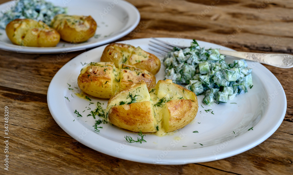 Baked potatoes with cheese and cucumber salad with sour cream. Selective focus.