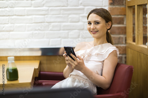 young woman sitting in a coffee shop with her phone