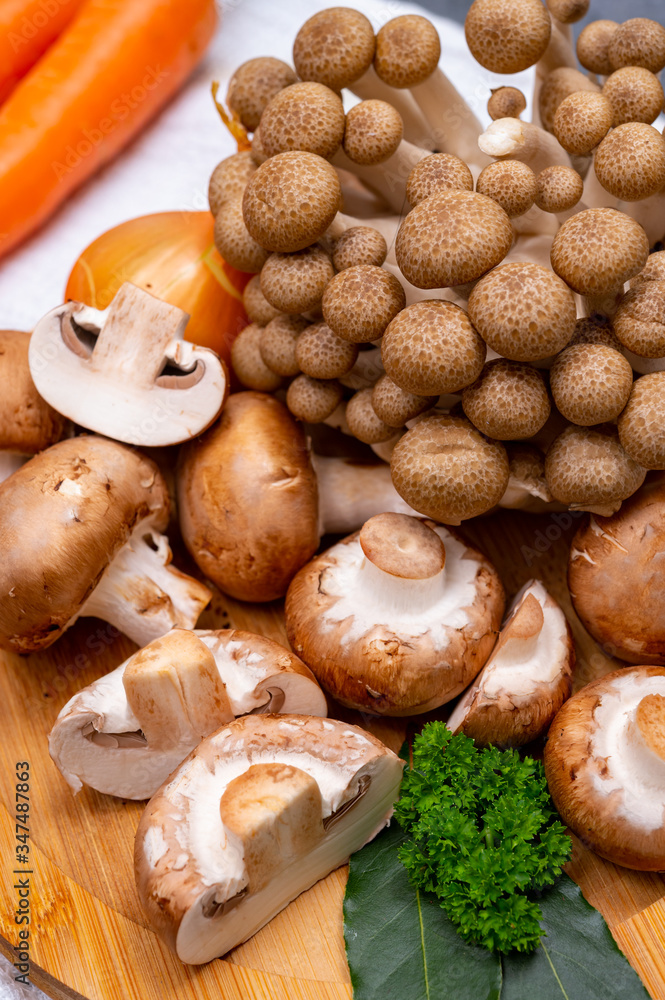 Fresh ingredients for tasty vegetarian mushrooms soup, brown champignons, buna shimeji, carrots Fresh ingredients for tasty vegetarian mushrooms soup, brown champignons, buna shimeji, carrots