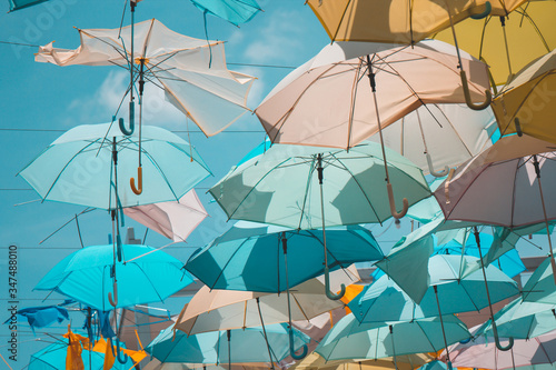Colorful umbrella hang as ceiling with blue sky. in teal blue or pastel color tone.