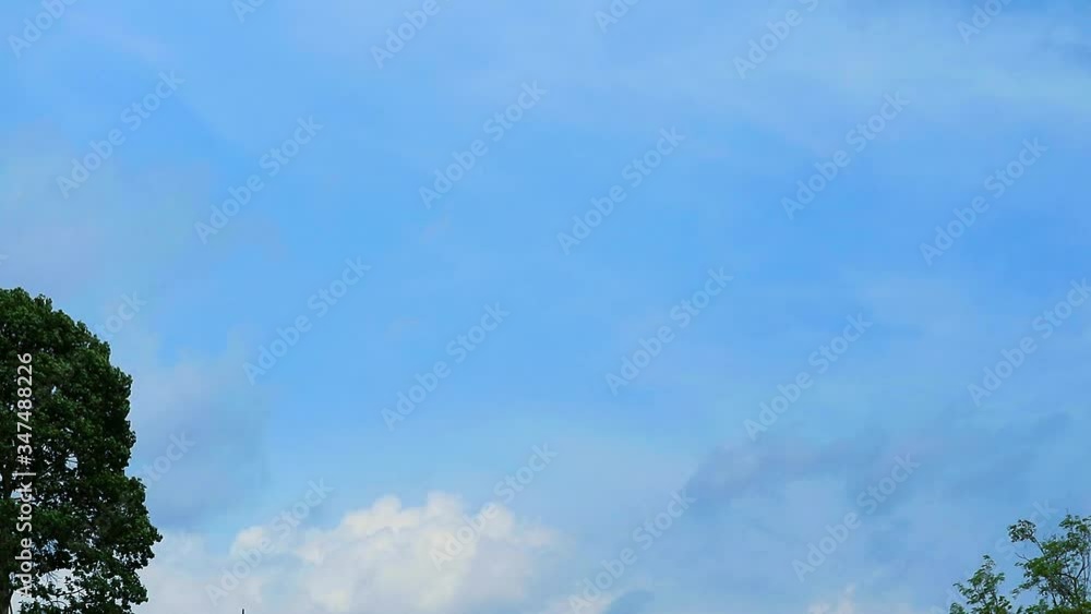 Beautiful blue sky with white clouds slow moving over tree in summer Beautiful blue sky with white clouds slow moving over tree in summer