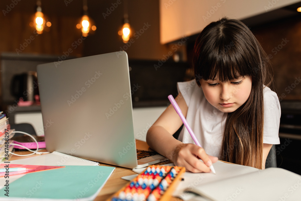 Schoolgirl does homework at home. Online learning with a laptop. Study with a video call. Distance education during quarantine Schoolgirl does homework at home. Online learning with a laptop. Study with a video call. Distance education during quarantine