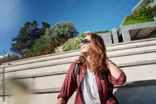 Young beautiful woman smiling happy and confident. Sitting on stairs with smile on face at the town street