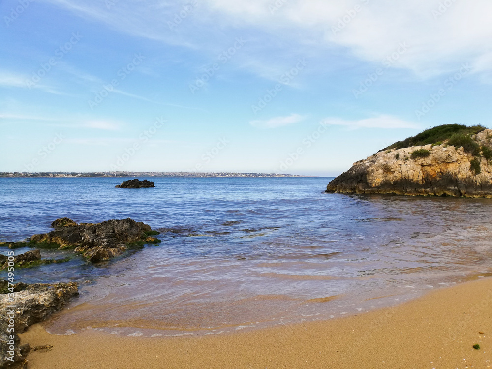 beautiful summer scenery. rocks on the sand. calm waves on the water. clouds on the sky. wide panoramic view