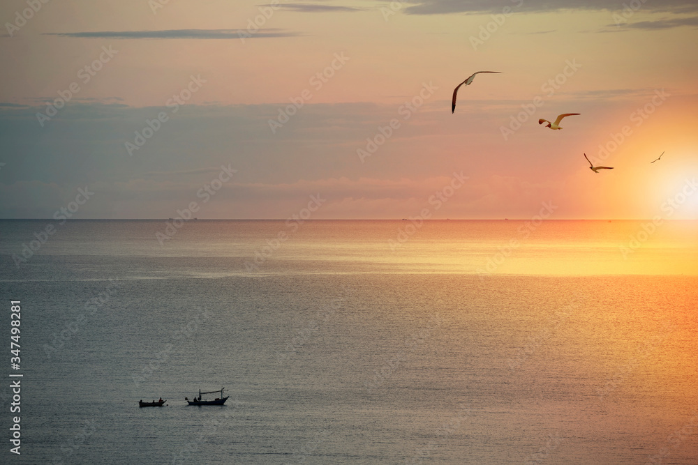 Fishing boat and seagulls in sunrise moment in the sea.