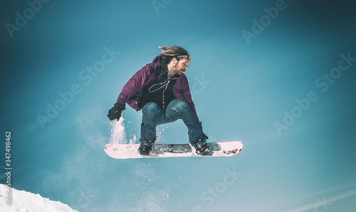 Freerider snowboarder doing speed trick air jump with his snowboard. Winter mountain freeride