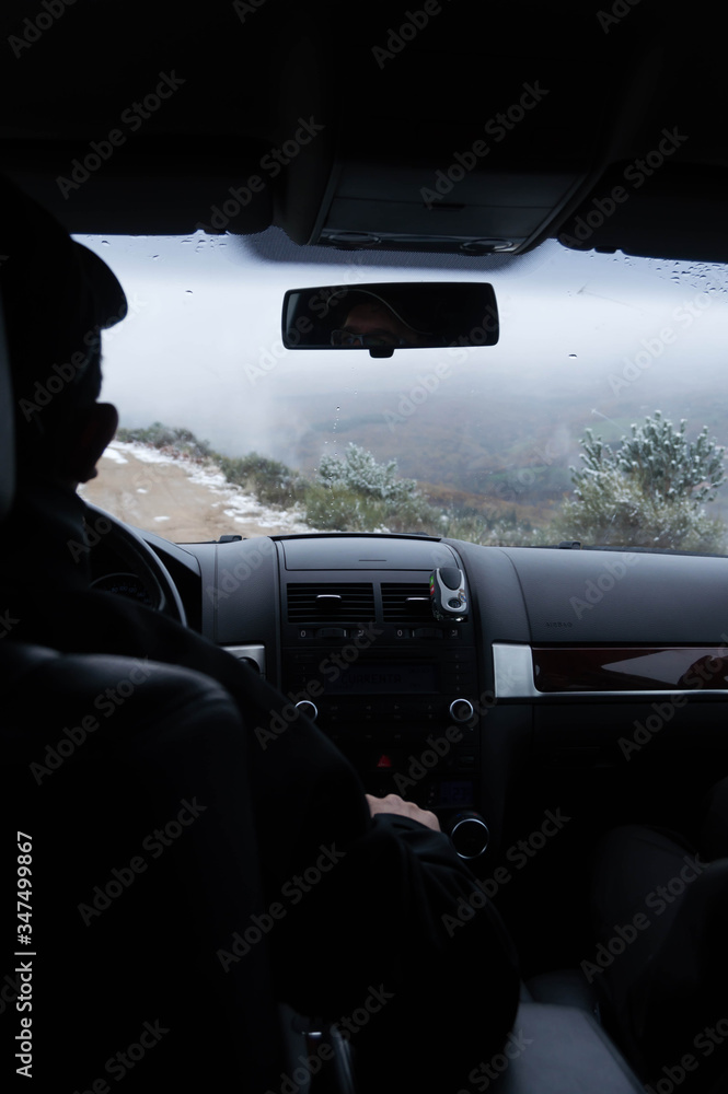 Silhouette of a man driving a car in the mountains