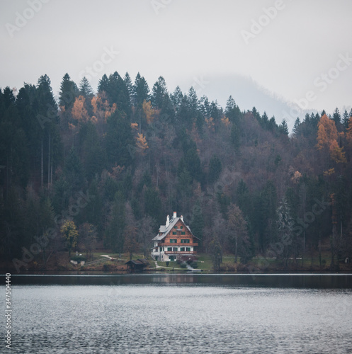 Moody morning on the lake with a house cabin and trees in background