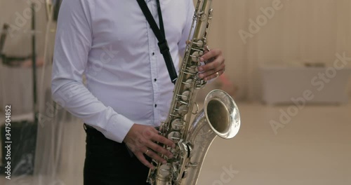 Man playing  the saxophone at a wedding in a nice restaurant.  Saxophone player. Musician playing sax, saxophonist at the party. Saxophonist at the wedding party playing music. photo