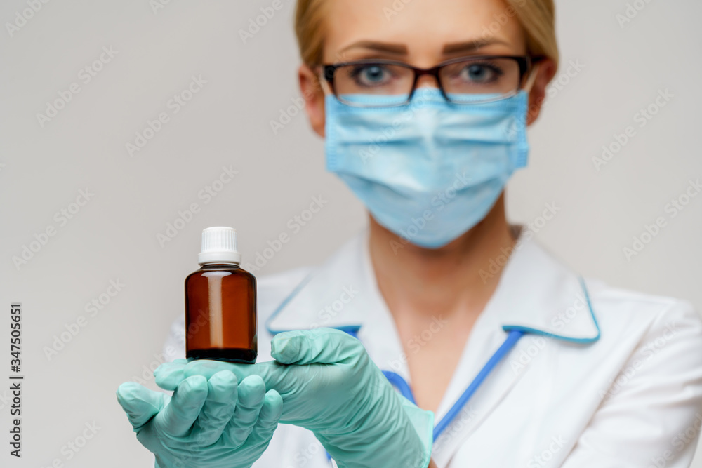 medical doctor nurse woman wearing protective mask and rubber or latex gloves - holding can of pills