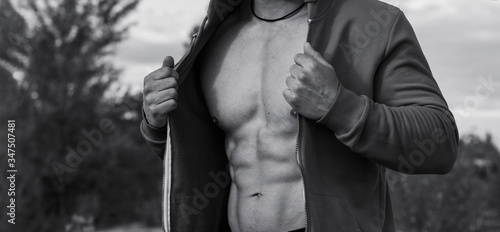 Black and white photo - close up of male muscular torso, during an outdoor sports training. Male power. © A Stock Studio