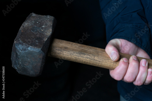 working sledgehammer in hands with notches for breaking walls on a dark background
